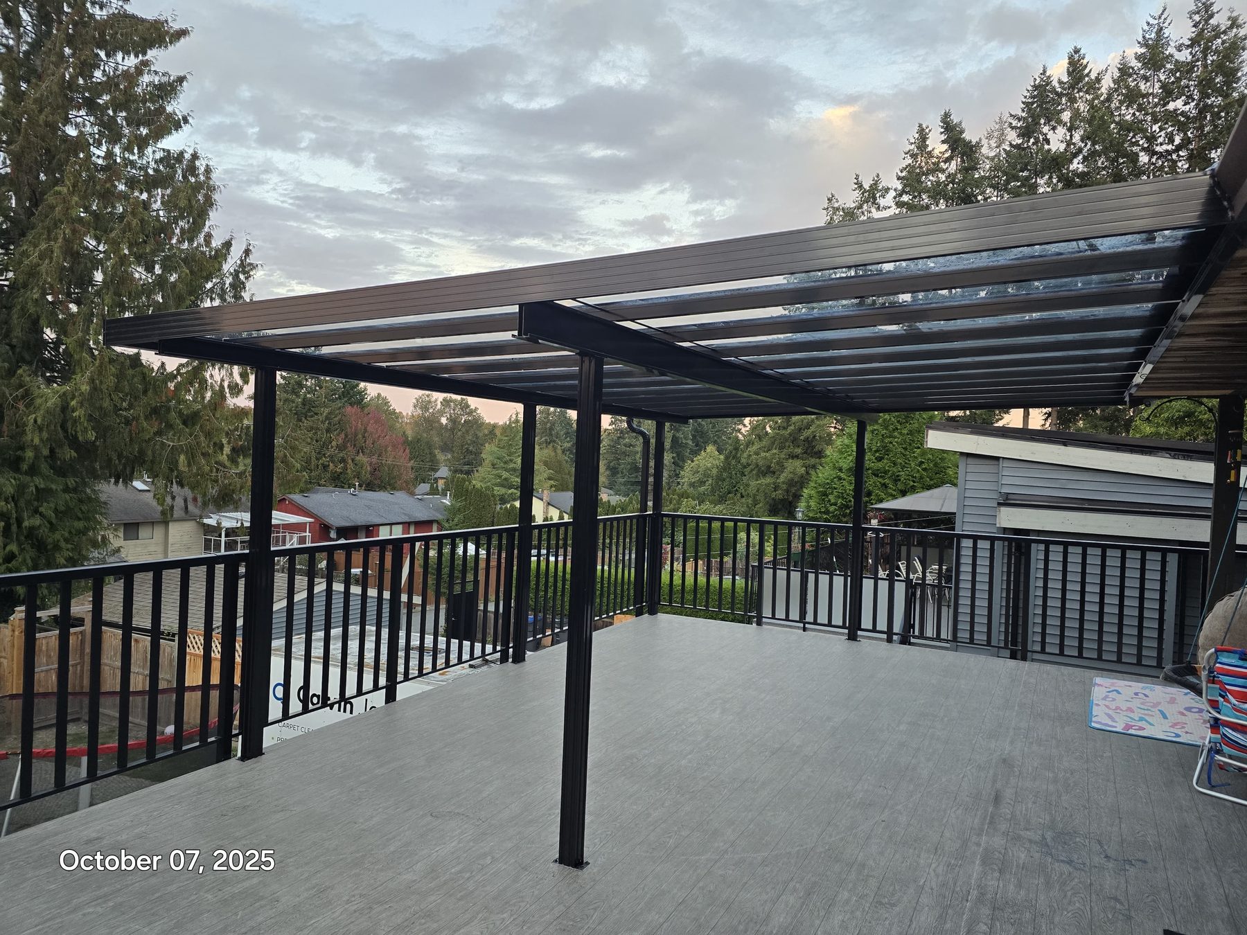 Glass-roof aluminum pergola over an upper deck with railing at dusk