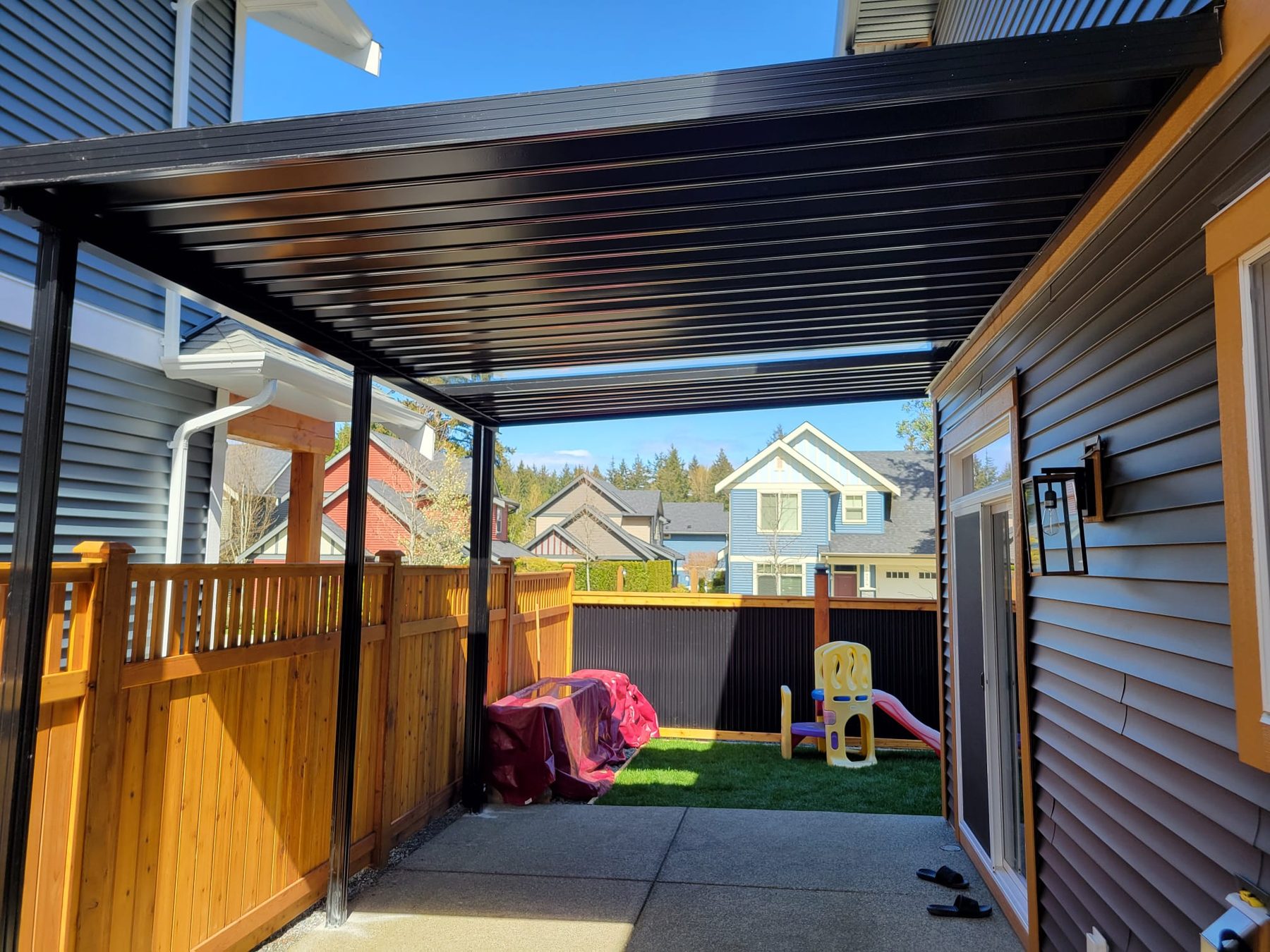 Freestanding black aluminum cover over a side-yard patio